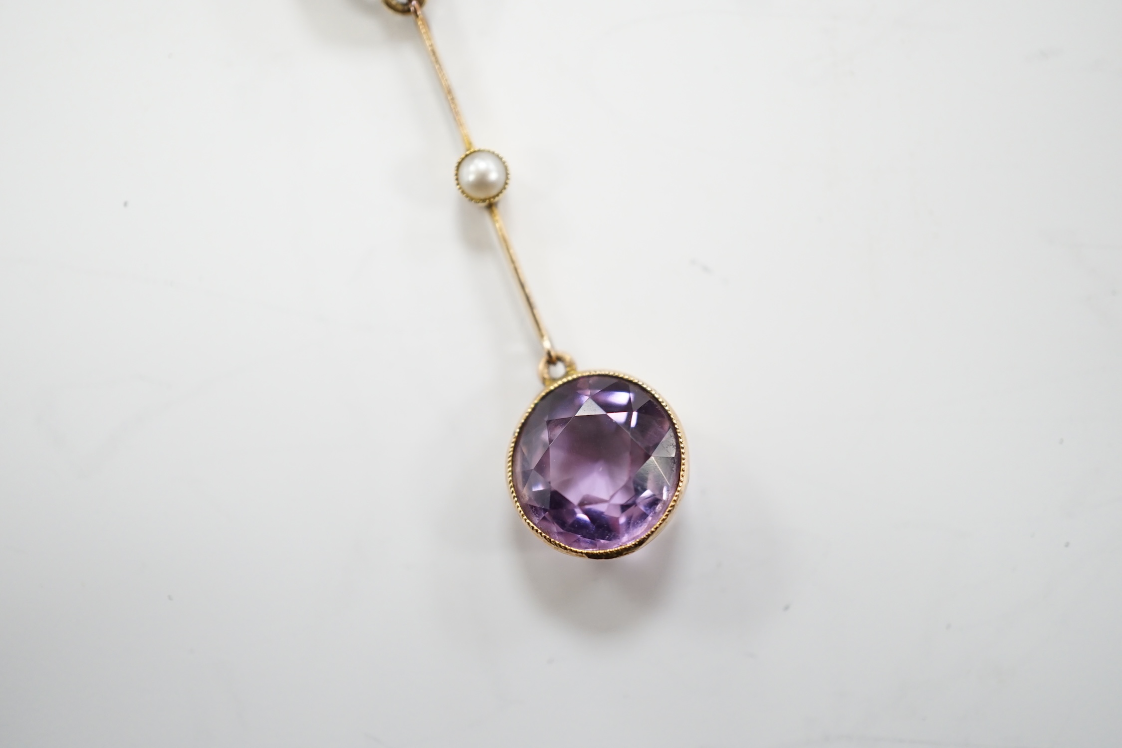 An Edwardian 9ct, two stone amethyst and single stone seed pearl set drop pendant necklace, gross weight 3.8 grams.